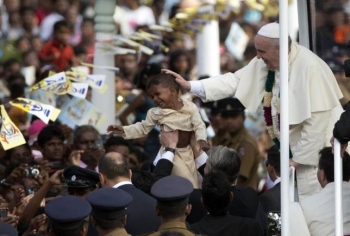Pope Francis blessing a child. From Reuters