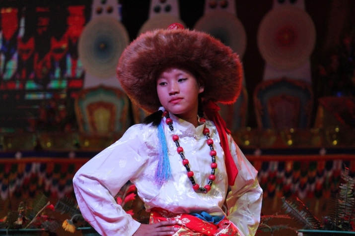 A Tibetan girl from the exiled community at Clement Town in Dehradun, dancing in front of large ritual <i>torma</i> on stage in Shravasti. November 2016. Image courtesy of the Drikung Kagyu Institute