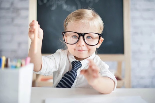 Young child with glasses and shirt and tie of a teacher