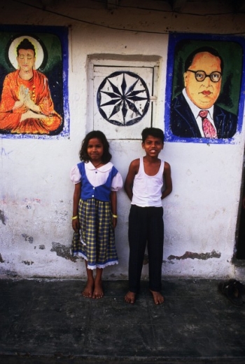 Dalit children standing by a portrait of the Buddha, a Dharma wheel, and Dr. Ambedkar. From thebuddhistcentre.com.