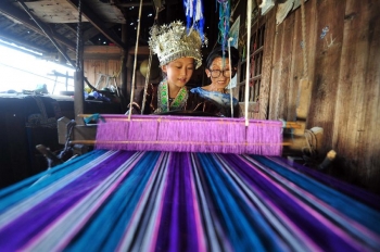 Liang Caiyun, a 10-year-old Miao girl, learns weaving from her grandma in Zhongping Village. From Xinhua.