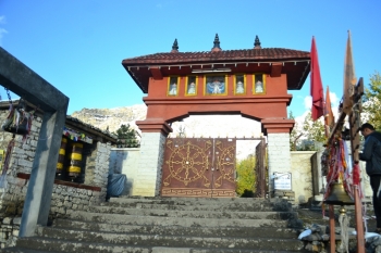 Main gate of Muktinath with Buddhist prayer wheels on one side and Hindu prayer bells