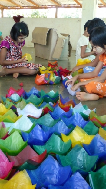 Children at Parahita Monastery making floating paper lanterns, which sell for 10 kyat each