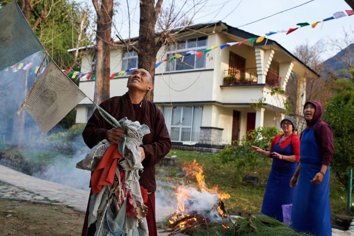 Old prayer flags being removed and burned while new ones are hung at Dolma Ling