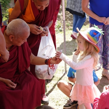 Lama Zopa Rinpoche giving children koala bears holding