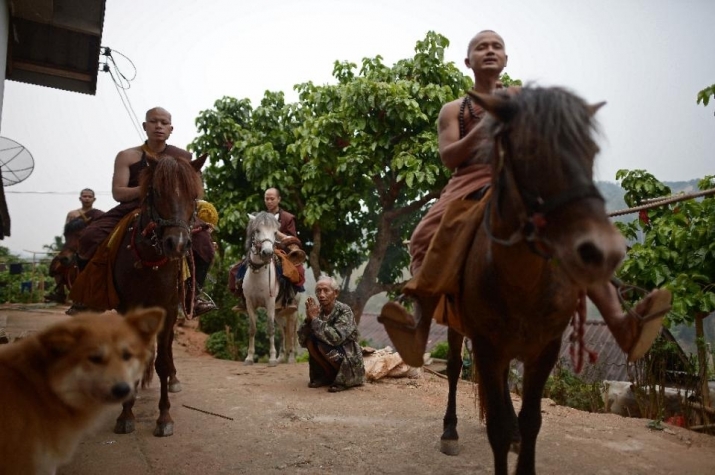 A resident makes an offering to horse-riding monks during their early morning alms round in the communities surrounding Golden Horse Temple in northern Thailand's Chiang Rai Province. From news.yahoo.com