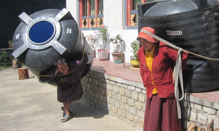 Head nun Ani Kunzang and a helper bringing water tanks up the mountain