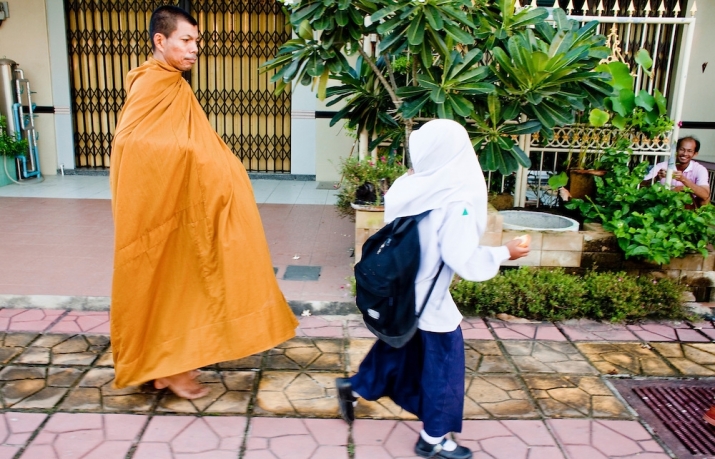 A Thai Muslim girl walks past a Thai Buddhist monk in Pattani, Thailand. Photo by Jack Kurtz. From photoshelter.com