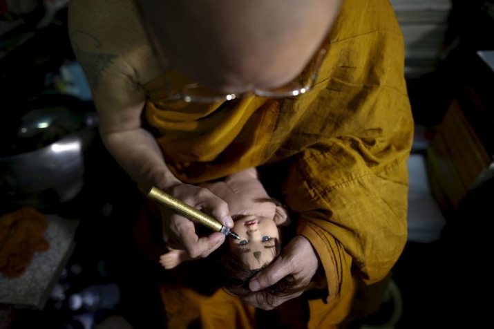 A Buddhist monk anoints a doll during a blessing ritual. Photo by Athit Perawongmetha. From reuters.com