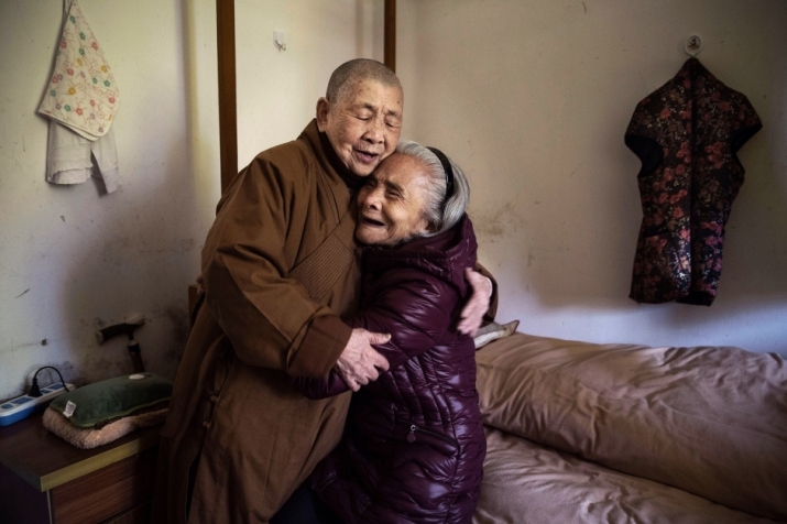 Buddhist nun Nen Qing, 81, hugs resident Luo Yudi, also 81, who has suffered a stroke. Photo by Kevin Frayer. From cbc.ca