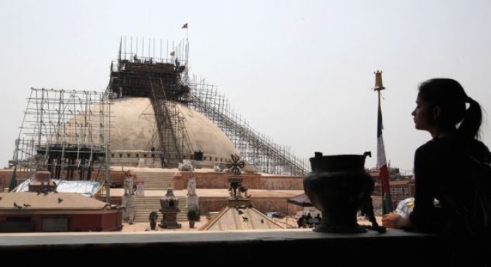 A Nepalese woman observes ongoing work to reconstruct the Boudhanath Stupa. From voanews.com