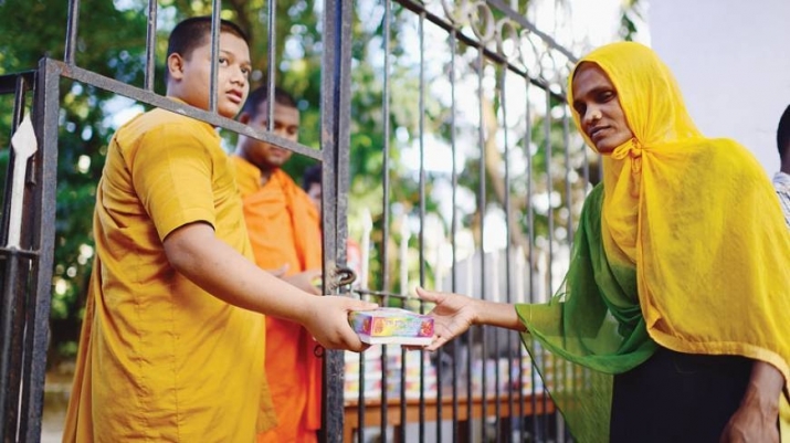 A monk gives food to a Muslim woman. From dhakatribune.com