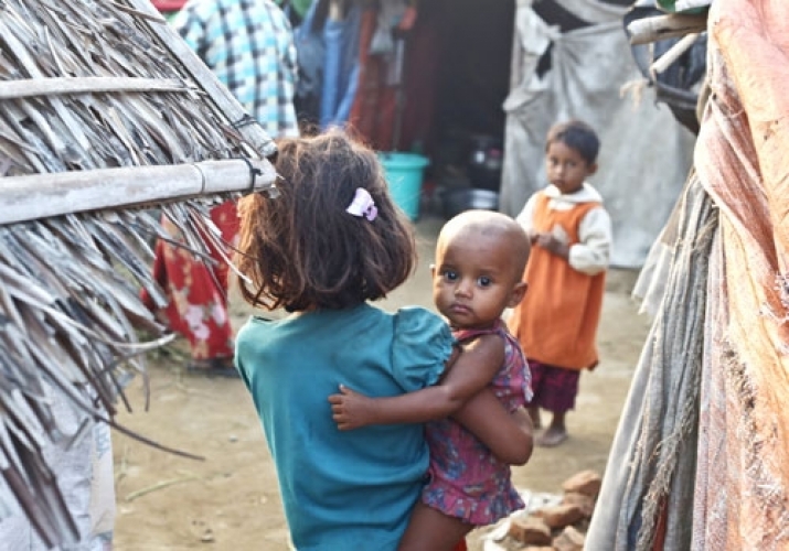 A young girl carries a toddler at a resettlement camp in Myanmar's Rakhine State. From mmtimes.com