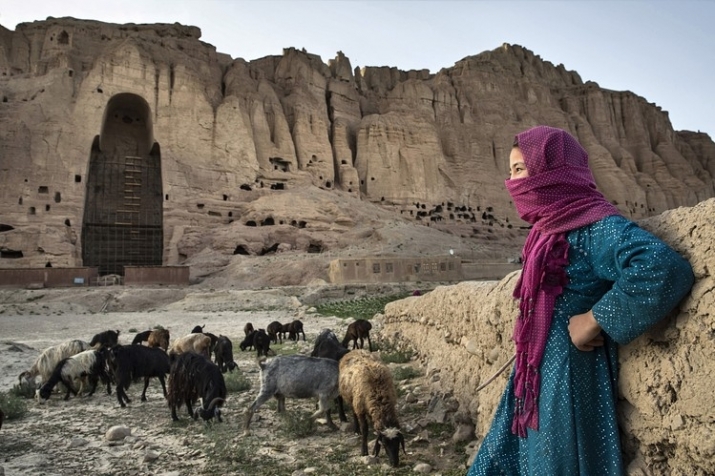 A girl watches over her sheep and goats as they graze before one of the destroyed Bamiyan Buddhas. From wsj.com