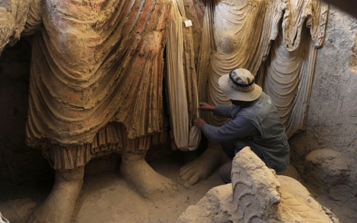 An archaeologist inspects Buddhist statues discovered inside an ancient monastery at Mes Aynak. From aljazeera.com
