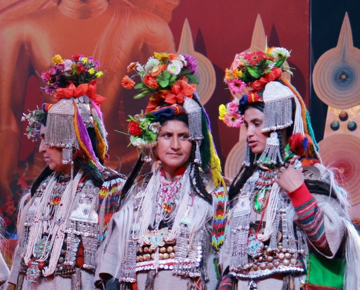 Three Brogpa Aryan women in their elaborate silver jewelry and floral headdresses prepare to dance for the assembled guests. November 2016. Image courtesy of the Drikung Kagyu Institute