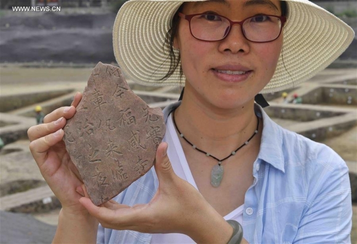Archaeologist Zhang Xufen shows a fragment of Buddhist tablet unearthed at the Fugan Temple excavation site. Photo by Liu Kun. From ecns.com