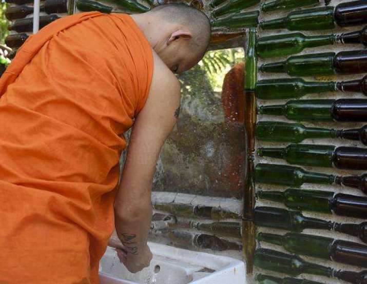 A monk washes his hands at a bottle wall at Wat Charok Padang in Malaysia. Photo by Seth Akmal. From themalaysianinsight.com