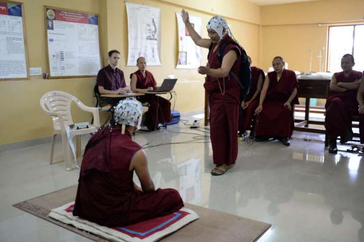 Monks engaged in a debate while wearing white EEG caps. From scienceformonks.org