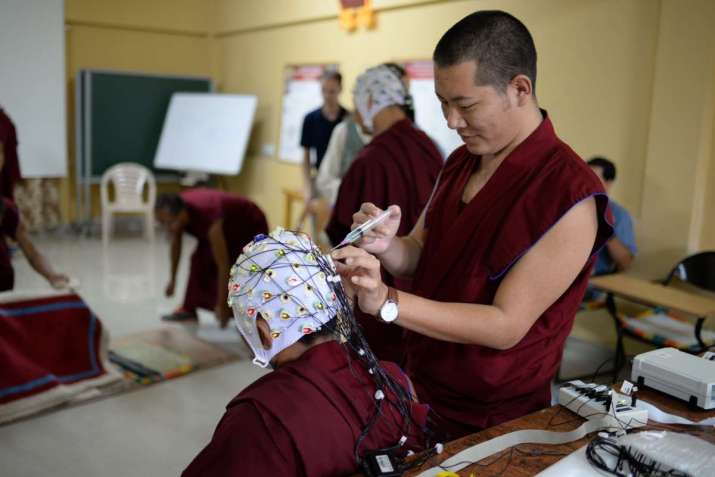 A monk applies a conductive gel to the electrodes of the EEG cap. From scienceformonks.org