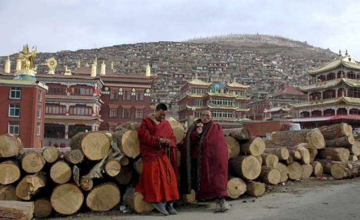 Buddhist monks stand in front of Larung Gar, in southwestern Sichuan Province. From japantimes.co.jp