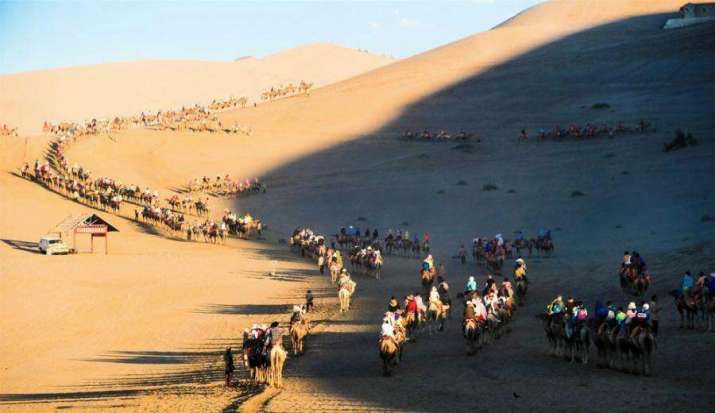 Tourists ride camels at a scenic spot near Dunhuang. More than 25,000 people visit Mogao daily during the peak summer period. Photo by Wang Binyin. From ecns.com