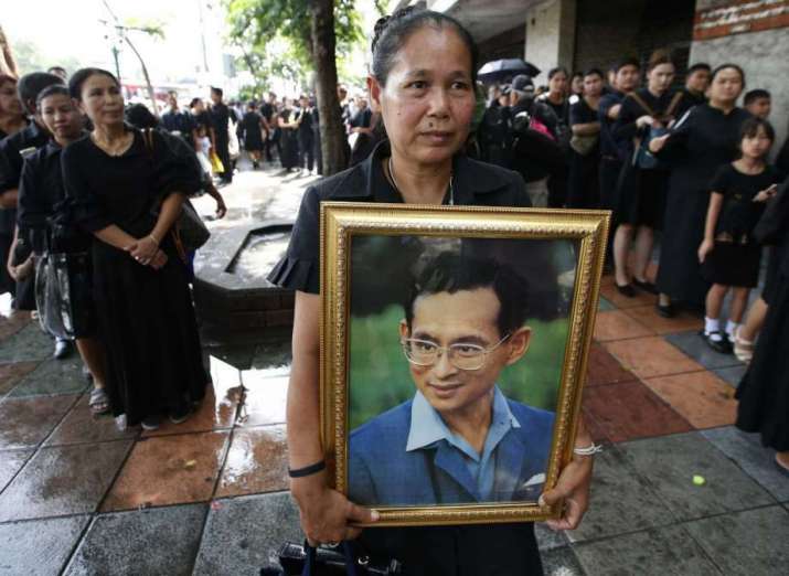 A mourners clasps a portrait of late Thai king outside the Grand Palace. From sfgate.com