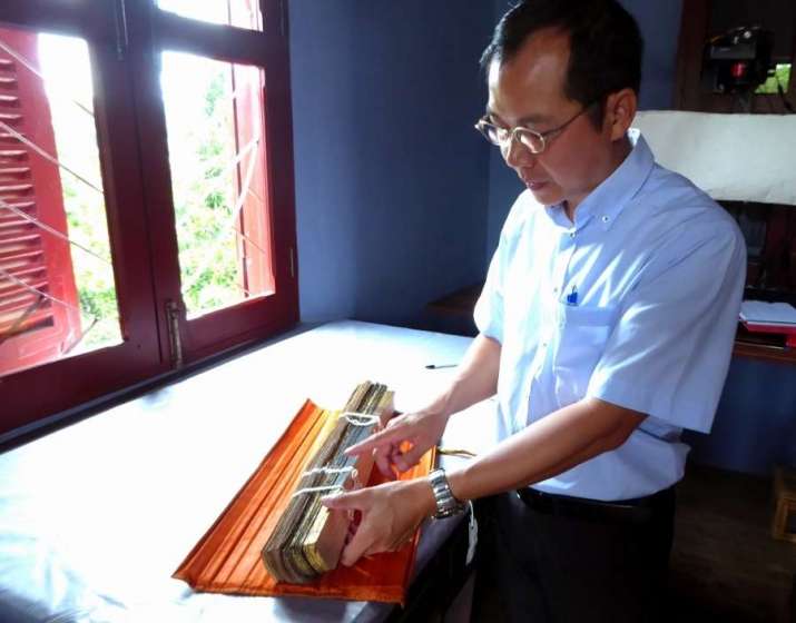 Dr. Khamvone Boulyaphonh, director of the Buddhist Archives of Luang Prabang, examines an old manuscript. Image courtesy of the author