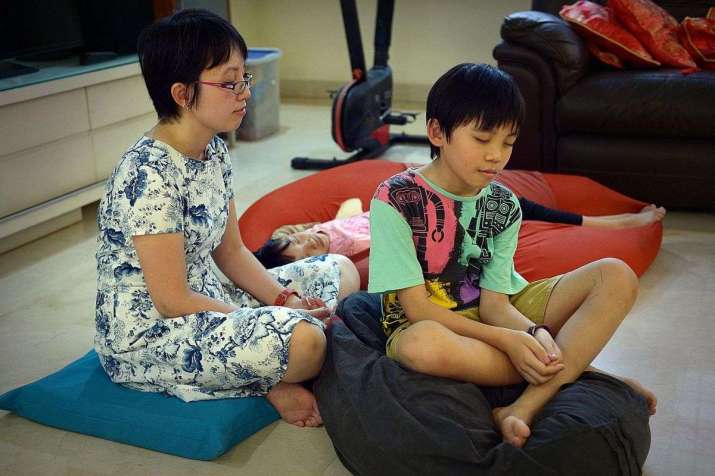 Dr Koh Li Wearn practicing meditation at home with her children, Jon Yew and Jean Anne. From straitstimes.com