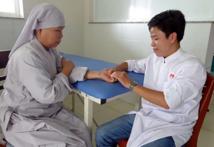 A male lay nurse checks the pulse of a monastic patient. Image courtesy of the author