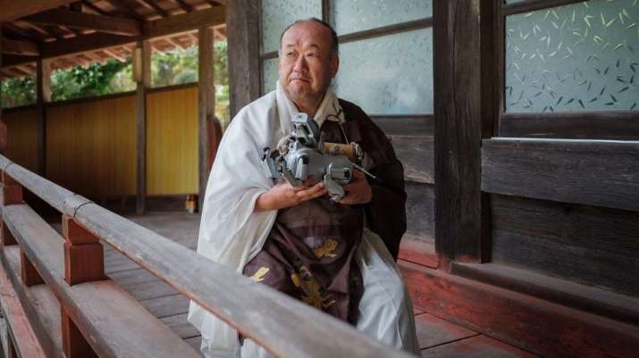 Head priest Bungen Oi holds a robot dog after a funeral at Kofuku-ji. From mashable.com