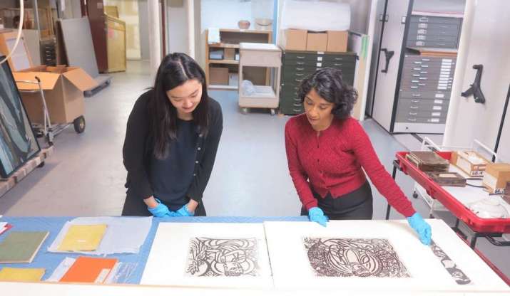 Research assistant Su Yen Chong with Haema Sivanesan examining woodcut prints by Shiko Munakata. From aggv.ca