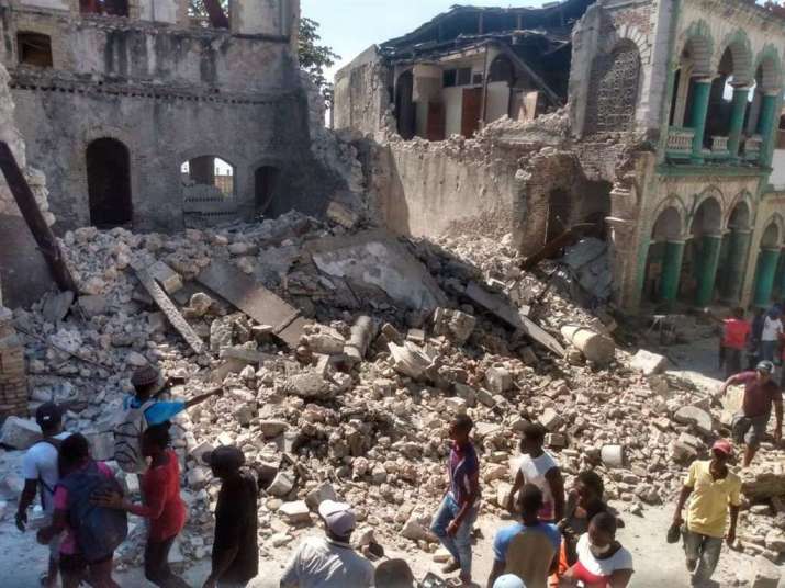 People walk by a collapsed building in Haiti after the 14 August earthquake. From focustaiwan.tw