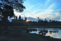 Angkor Wat at sunrise. In this magical moment, the sun makes a grand entrance on the eastern horizon, first peeking shyly from one of the gopurams and then sailing gracefully above them to illuminate the world.